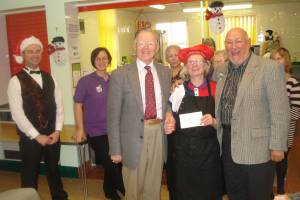Pictured left to right are President of the Rotary Club of Crewe Derek Poppleton, Cheshire Academy Director Jane Whetnall with the cheque and District 1050 Foundation Chairman Mike Payne.In the background are Academy volunteers who served the Xmas Lunch